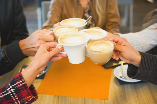 Groep vrienden drinken koffie in de bar en toasten met elke o - Foto, afbeelding