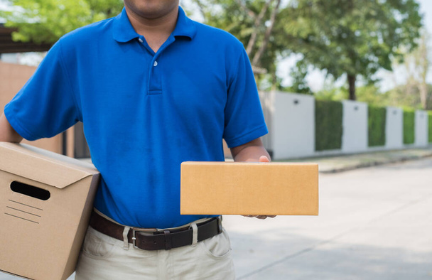 Uomo di consegna blu che tiene scatola di cartone pacchi
. - Foto, immagini
