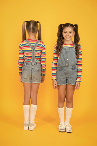 Stylish and confident. compare little girls yellow background. hairdresser salon. kid summer fashion. beauty and style. childhood life. happy school friendship. best friends. small sisters have fun - Φωτογραφία, εικόνα
