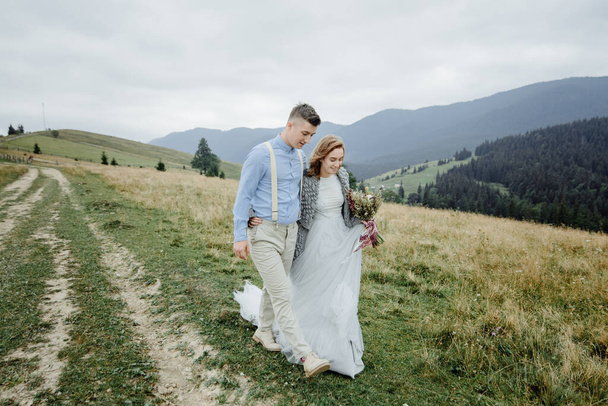 Photoshoot of the bride and groom in the mountains. Boho style wedding photo. - Foto, afbeelding