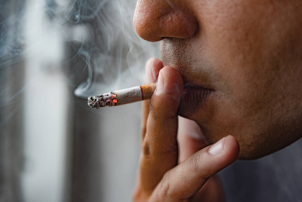 Крупним планом молодий чоловік курить цигарку
. - Фото, зображення