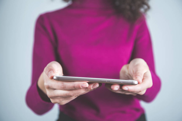 woman hand smart phone on grey background - Foto, Imagen