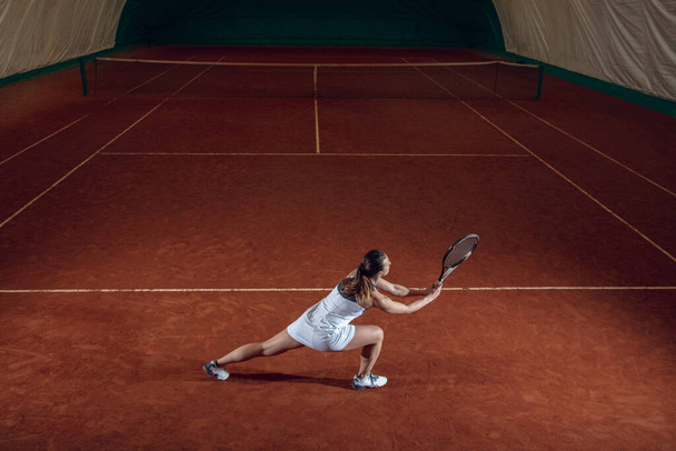 Young caucasian professional sportswoman playing tennis on sport court background - Zdjęcie, obraz