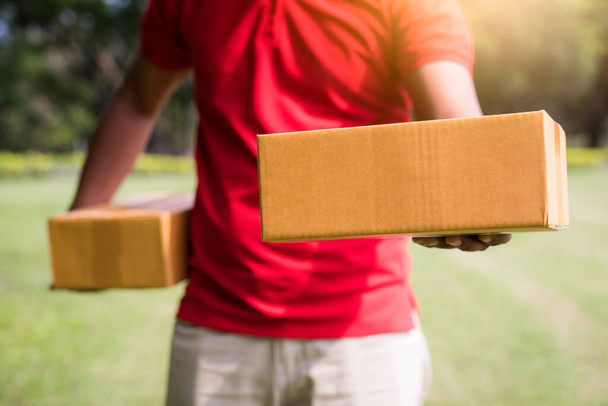 Чоловік доставки в червоній уніформі з картонною коробкою
 - Фото, зображення