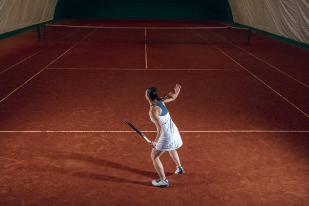 Young caucasian professional sportswoman playing tennis on sport court background - Fotó, kép