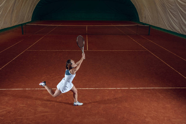 Young caucasian professional sportswoman playing tennis on sport court background - Fotoğraf, Görsel