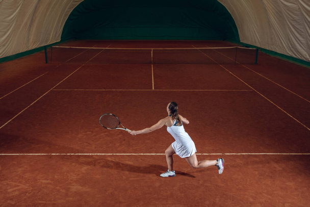 Young caucasian professional sportswoman playing tennis on sport court background - Fotografie, Obrázek