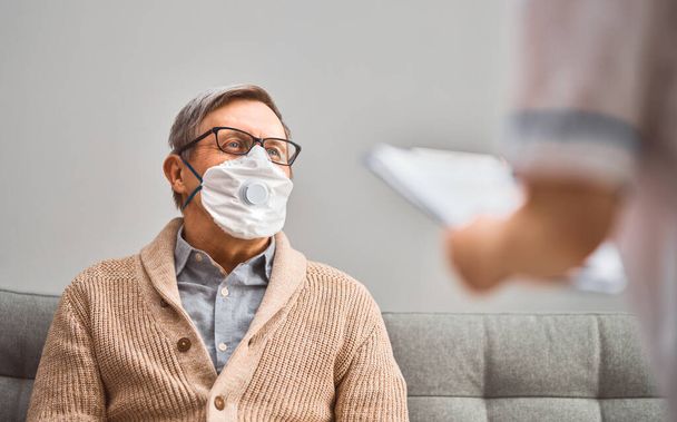 Doctor and senior man wearing facemasks during coronavirus and flu outbreak. Virus and illness protection, home quarantine. COVID-2019 - Foto, Imagen