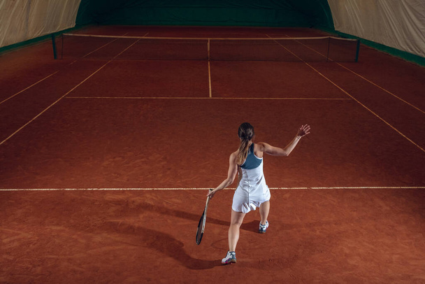 Young caucasian professional sportswoman playing tennis on sport court background - Фото, изображение