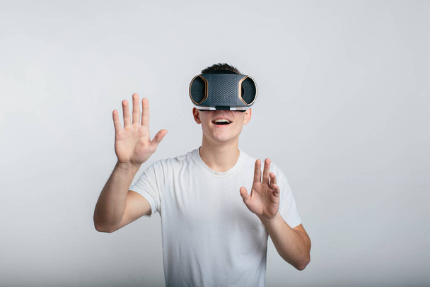 Man wearing virtual reality goggles. Studio shot, gray backgroun - Photo, image