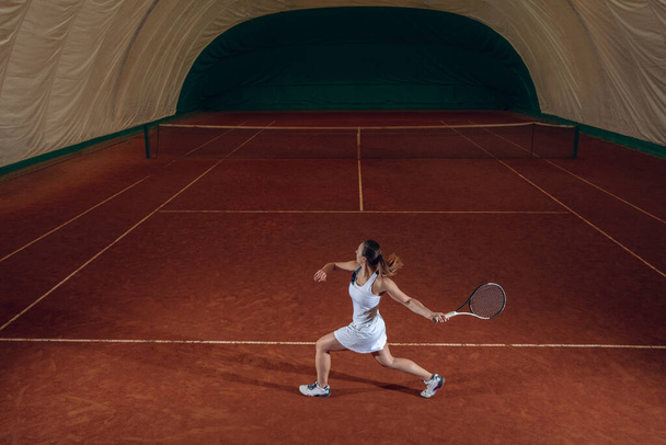 Young caucasian professional sportswoman playing tennis on sport court background - Photo, image