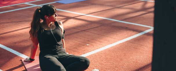 Kaukasische attraktive Frau in Sportkleidung macht Pause nach dem Laufen draußen - Foto, Bild