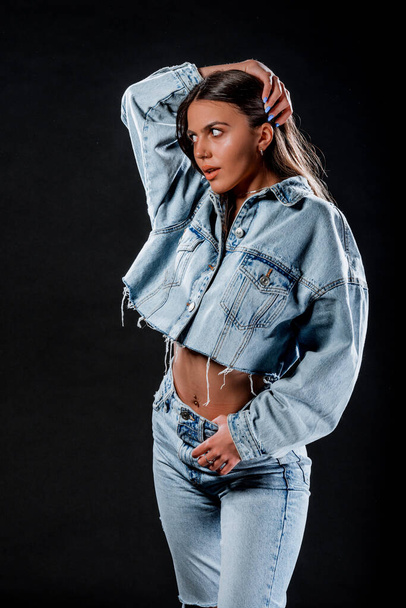 Portrét atraktivní trendy dívky v modré džínové bundě a roztržené džíny pózující - Fotografie, Obrázek