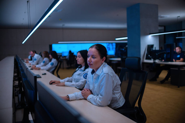 Groep van Security datacenteroperators (beheerders) die in een groep werken in een CCTV-monitoringruimte, terwijl ze naar meerdere monitoren kijken (computerschermen)) - Foto, afbeelding