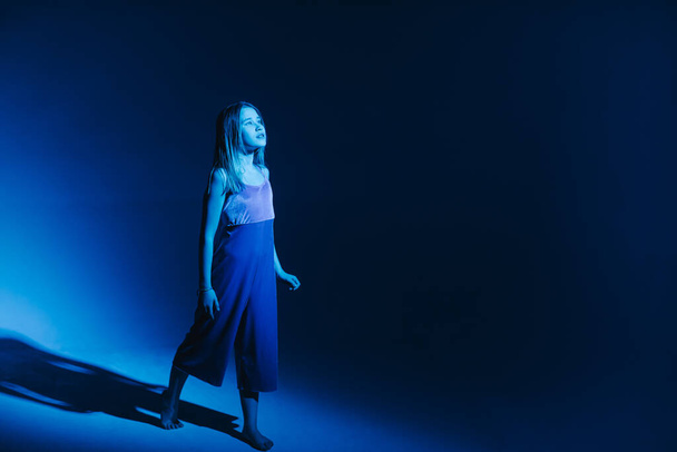 Молодая стильная девушка танцует в студии на цветном неоновом фоне. Классический танцор
. - Фото, изображение