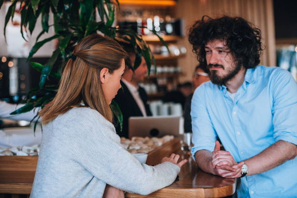 Modern couple drinking coffee and talking with each other during a meeting - Photo, Image
