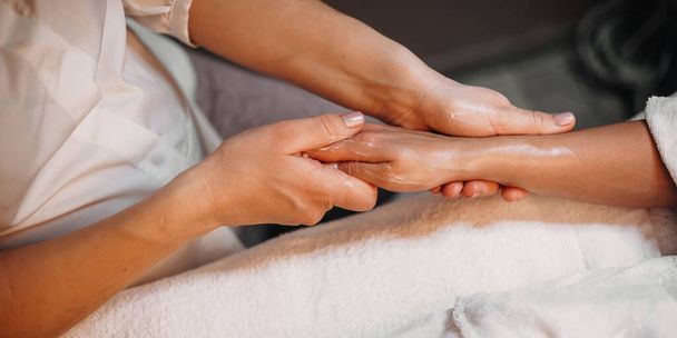 Sesión de masaje de manos con crema especial realizada en el salón de spa a una joven
 - Foto, imagen