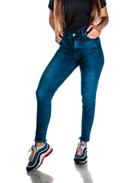 Studio moda portret nowoczesnej dziewczyny w stylowe spodnie jeansowe i sportowe senakers - Zdjęcie, obraz