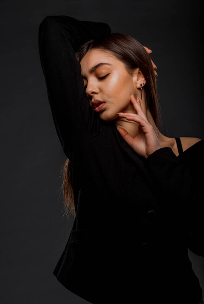 Stylish young woman wearing black clothing isolated on black wall - Foto, immagini