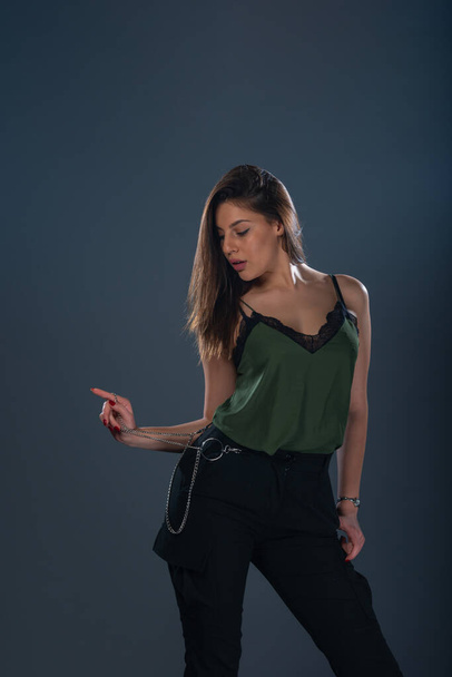 Портрет сексуальної молодої жіночої моделі, що стоїть в студії і носить темно-зелений верх і чорні штани
 - Фото, зображення