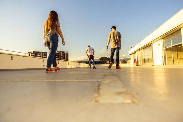 Young people amuse on the rooftop of the building while riding skateboard - Foto, Imagem