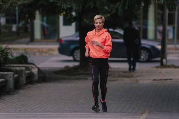 Athletic fit female runner running in an urban environment - Photo, Image