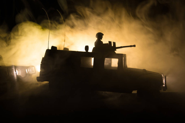 Έννοια πολέμου. Σκηνή μάχης στο φόντο του ουρανού ομίχλη πολέμου, Καταπολέμηση σιλουέτες κάτω από συννεφιά Skyline τη νύχτα. Στρατιωτικό όχημα με διακόσμηση έργων τέχνης στρατιωτών. Επιλεκτική εστίαση - Φωτογραφία, εικόνα