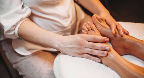 Kaukasische masseur met een been massage sessie met de cliënt liggend op de bank - Foto, afbeelding