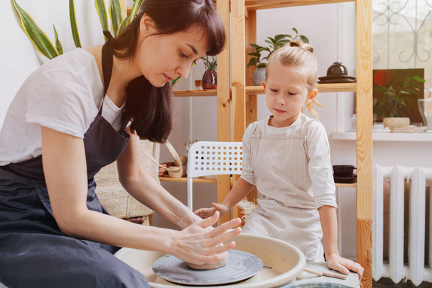 Pottery studying class. She passes her experience to a young follower in the pottery studio. - Foto, Imagem