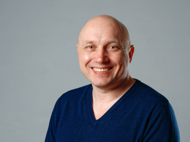 Πορτρέτο ενός φαλακρού χαρούμενος άνθρωπος σε ένα γκρι φόντο 2020 - Φωτογραφία, εικόνα