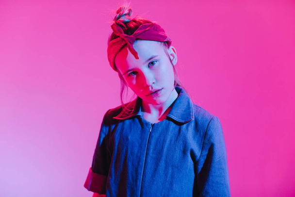 Junge stilvolle Mädchen im Studio auf einem farbigen Neon-Hintergrund. Musik-DJ-Plakatgestaltung. Porträt einer jungen Tänzerin. - Foto, Bild