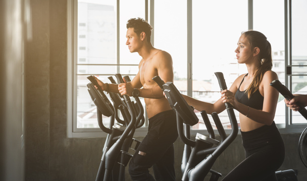 Group of people at the gym exercising on the cross trainer machine. Young fitness men and women doing cardio workout program for beginner. - Photo, Image
