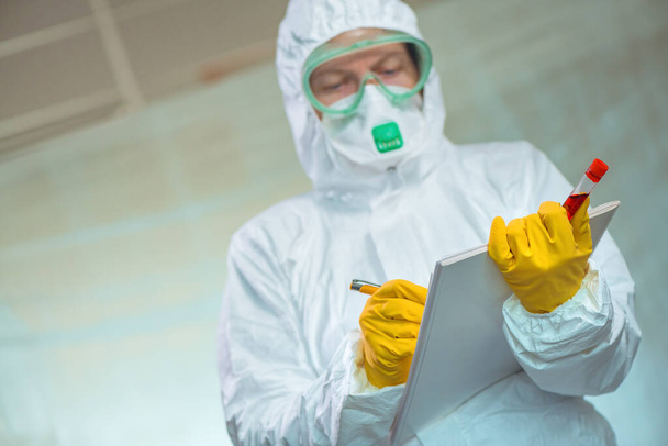 Virologist with blood test sample lab tube writing notes in virus quarantine - Foto, Imagem