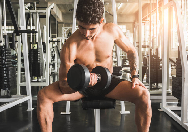 Forte exercício homem muscular no ginásio fazendo exercícios no bíceps. Conceito de treinamento de peso
. - Foto, Imagem
