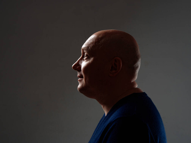 Portrait of a bald cheerful man in profile on a black background 2020 - Фото, изображение