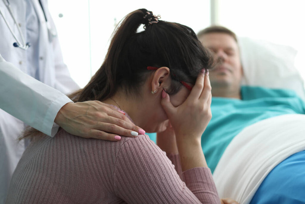 Mujer en clínica llorando cerca de hombre en cama de hospital
 - Foto, imagen