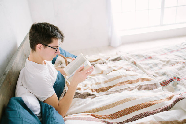 Чоловік читає книгу на своєму ліжку вдома
 - Фото, зображення