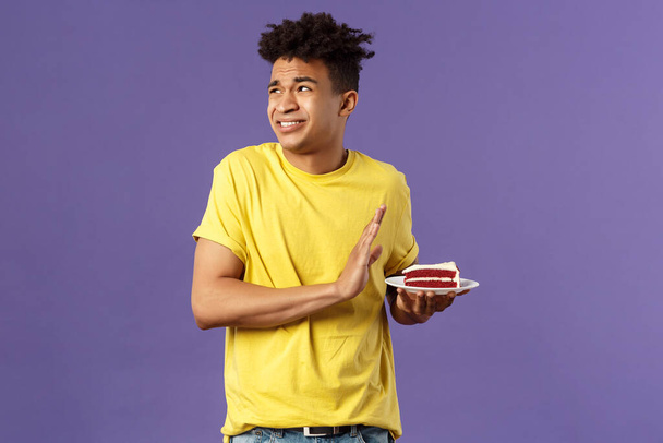 Celebration, party and holidays concept. Oh gosh its disgusting. Portrait of reluctant and displeased young man turn away from awful bad taste cake, show refusal, rejection or stop sign - Photo, Image