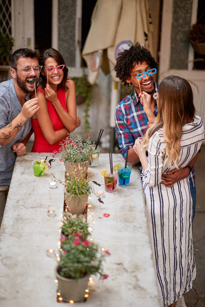 Молодые счастливые друзья в кафе веселятся с реквизитом
 - Фото, изображение