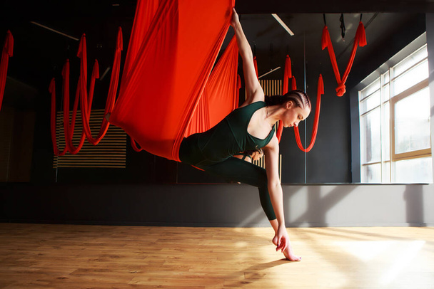 Young woman aerostretching, aerial yoga concept.  - Foto, Bild
