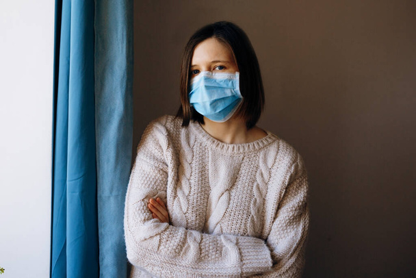 Portret młodej kobiety noszącej medyczną maskę na twarz, chroniącą przed wirusami, zarazkami i bakteriami podczas epidemii koronawirusów i grypy. Patrząc w kamerę, z bliska. - Zdjęcie, obraz