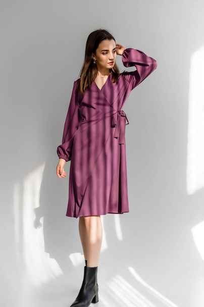 Attractive brown-haired woman in a purple checkered dress on a white background. Photosession for a clothing catalog - Φωτογραφία, εικόνα