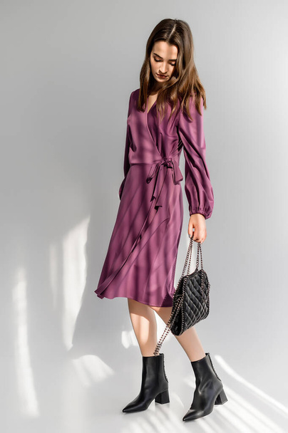 Attractive brown-haired woman in a purple checkered dress on a white background. Photosession for a clothing catalog - 写真・画像