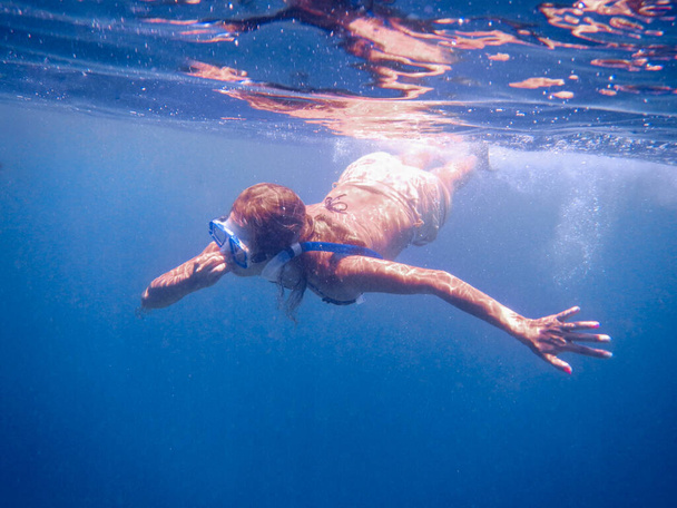 Een vrouw maakt snorkelen in het blauwe open water - Foto, afbeelding