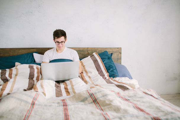 casual young man using laptop in bed at home - Valokuva, kuva