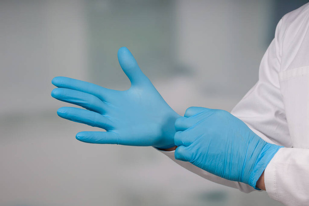 close-up van de hand van de arts het aantrekken van medische handschoenen  - Foto, afbeelding