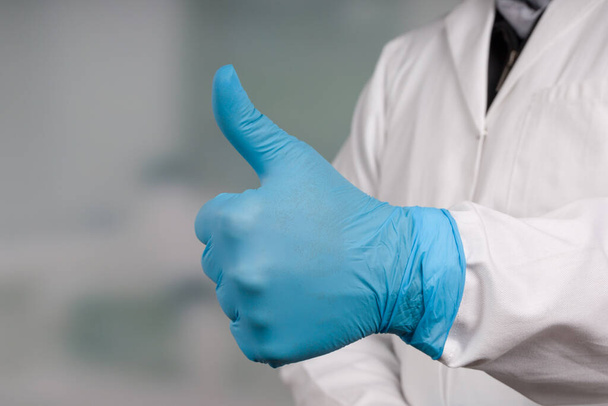 Dokter 's hand in medische handschoenen toont duimen omhoog - Foto, afbeelding