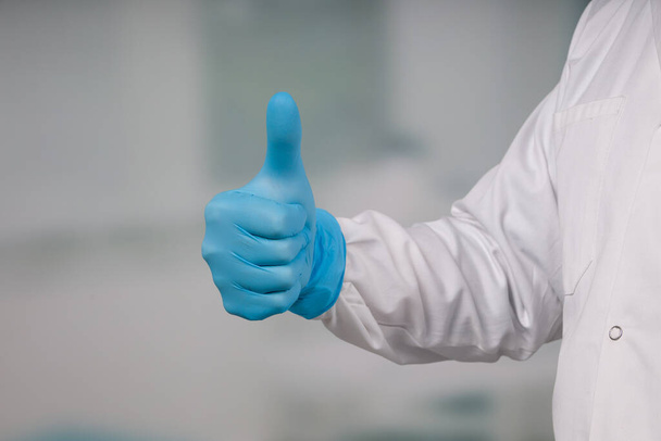 Mão de médico em luvas médicas mostrando polegares para cima
 - Foto, Imagem