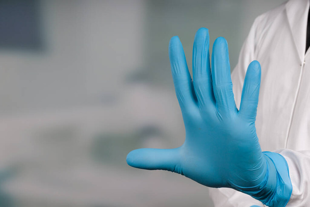Рука врача в медицинских перчатках показывает остановку, вход в карантинную зону запрещен
  - Фото, изображение