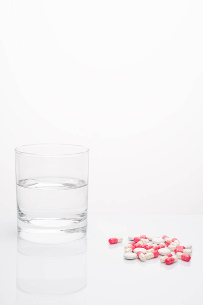 Pills capsules medicine and glass of water on white background. - Fotoğraf, Görsel